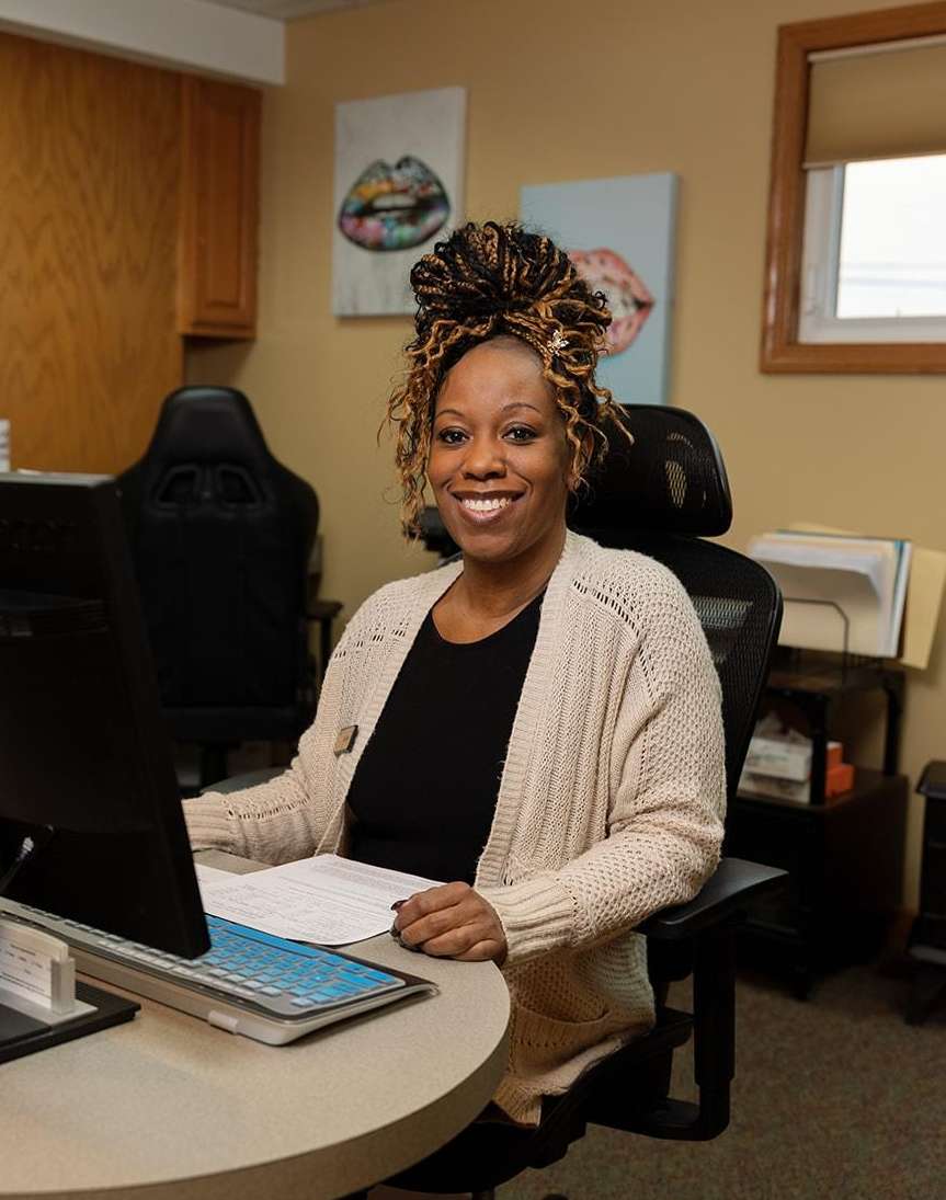 Receptionist smiling at front desk of dentist office in Hermitage PA